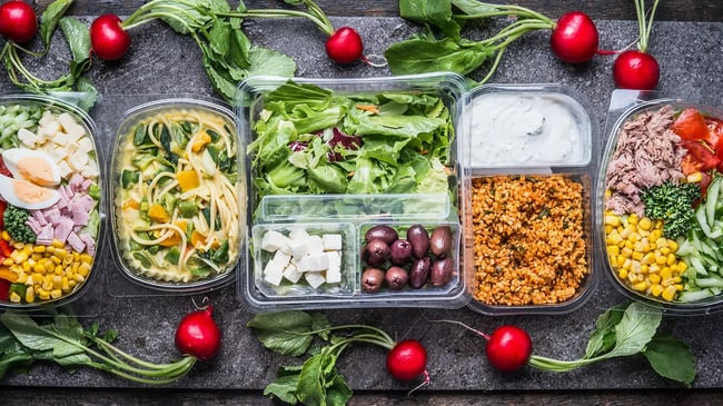 Das Bild zeigt Lebensmittel wie Salat, Feta-Käse und Oliven, die unter Schutzgas-Atmosphäre verpackt sind.